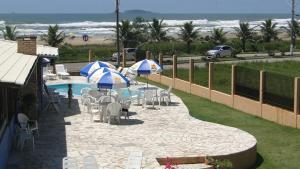 因比图巴Pousada Praia da Villa的游泳池旁带椅子和遮阳伞的天井