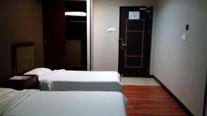 哥打京那巴鲁萨冬88酒店的一间酒店客房,设有两张床和一扇门