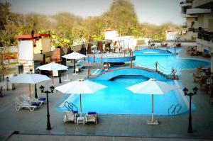 亚历山大AIFU Hotel El Montazah Alexandria的一个带遮阳伞和桌椅的大型游泳池