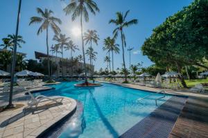 嘎林海斯港Marulhos Suítes Resort by MAI的一座棕榈树和椅子的大型游泳池