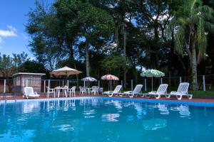 伊茹伊Hotel Jardim Europa的一个带桌椅和遮阳伞的游泳池