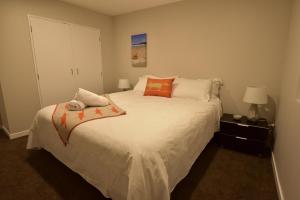 奥克兰埃普索姆公寓的卧室配有带橙色枕头的大型白色床
