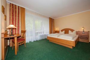 米滕瓦尔德拉尔晨航旅馆的一间卧室配有一张床、一张书桌和一个窗户。