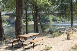 温索普Methow River Lodge的河边的野餐桌和长凳