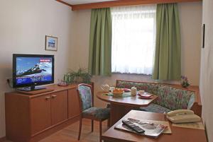上陶恩Hotel Bella的客厅配有电视、桌子和沙发