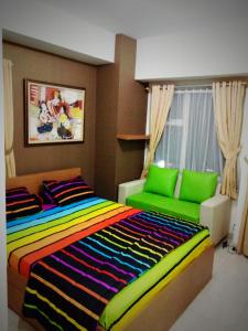 德波Wjy Apartment Margonda Residence 5的一间卧室配有色彩缤纷的床和绿色沙发