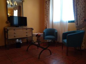 Belvis de MonroyHotel Alonso de Monroy的客厅配有两把椅子、梳妆台和电视