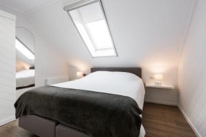 OosterblokkerChez Marly的卧室配有一张白色大床和两个窗户