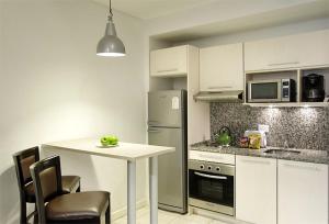 布宜诺斯艾利斯皮卡路加公寓酒店的厨房配有白色橱柜和桌椅