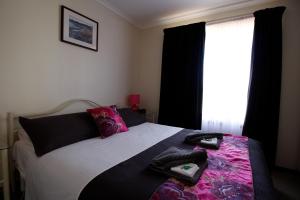 开普敦杰维斯凯普杰维斯度假屋的一间卧室配有一张带黑色和粉色床单的床和窗户。