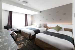 富山东急富山卓越大酒店的酒店客房设有三张床和一张桌子