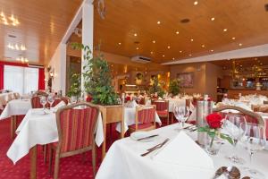 哈伦贝格海斯伯纳杜鹃酒店的餐厅设有白色的桌椅和玫瑰花