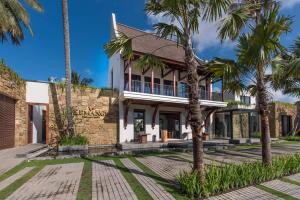 龙目岛库塔可曼格住宿加早餐旅馆 的前面有棕榈树的房子