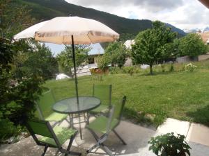 布里昂松Le chalet的庭院内桌椅和遮阳伞