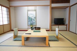 丰冈市翠山庄日式旅馆的配有桌椅和电视的客房