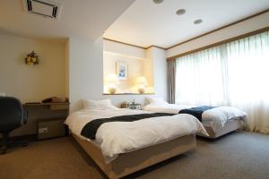 丰冈市翠山庄日式旅馆的一间卧室设有两张床和窗户。