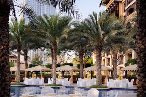 迪拜迪拜市中心皇宫酒店的棕榈树、白色椅子和遮阳伞的度假村