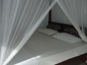 本托塔New Jaya Villa的一张带白色窗帘和枕头的床