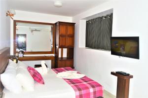 平纳瓦拉品纳兰达酒店的卧室配有一张床,墙上配有电视。