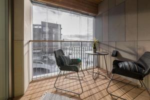 塔林Tallinn Premium Apartments的阳台配有两把椅子和一张桌子,还有一个窗户。
