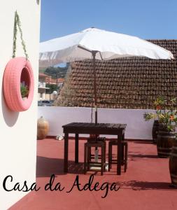 奎恩塔杜安乔Casa da Adega的一张带白色雨伞的桌子和一张带椅子的桌子