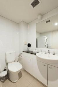 悉尼海滨大道一室公寓的白色的浴室设有卫生间和水槽。
