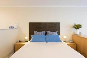 悉尼海滨大道一室公寓的一间卧室配有一张带蓝色枕头的大床