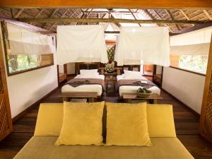 马尔多纳多港因卡特拉哈欣达山林小屋的一间设有四张床和白色窗帘的房间