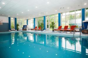 辛德尔芬根斯图加特辛德芬根梅斯美居酒店的一个带红色椅子的游泳池和一个大窗户
