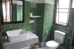 清莱班瓦拉博德酒店的绿色瓷砖浴室设有水槽和卫生间