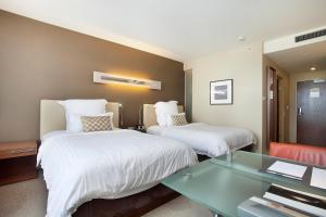 悉尼铂尔曼悉尼奥林匹克公园酒店的酒店客房,设有两张床和一张玻璃桌