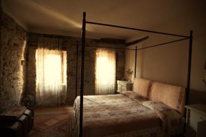 PolinagoCastello di Brandola的一间卧室设有天蓬床和2个窗户