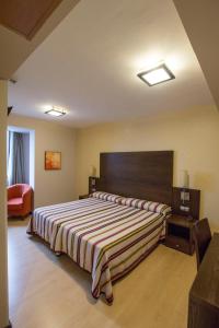 Las Infantas于勒卡酒店的一间卧室配有一张带条纹毯子的大床