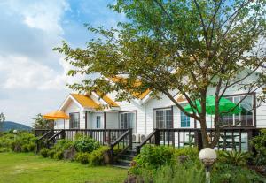 西归浦市艺术之家度假屋的白色的房子,有栅栏和树