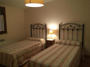 AbayLos Abetos的一间卧室设有两张床和一张桌子上的台灯。