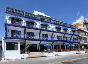 垦丁大街垦丁海岸旅店的白色的建筑,设有蓝色的阳台,位于街道上