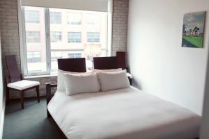 多伦多奥绸酒店的一间卧室配有一张带白色床单的床和一扇窗户。