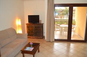 圣玛丽亚Apartment | in Tropical Resort | pool | close to beach的带沙发和电视的客厅以及阳台。