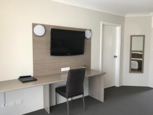 库纳巴拉布兰相思树汽车旅馆的一间设有一张桌子的房间,墙上有一台电视机