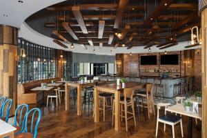 迪拜Copthorne Lakeview Executive Apartments Dubai, Green Community的一间带木桌椅的餐厅和一间酒吧
