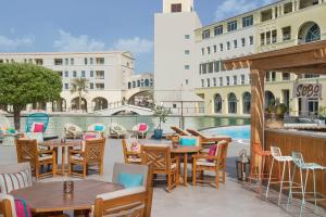 迪拜Copthorne Lakeview Executive Apartments Dubai, Green Community的一个带桌椅的庭院和一个游泳池