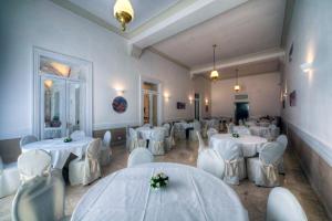 庞贝维多利亚餐厅酒店的用餐室配有白色的桌子和白色的椅子