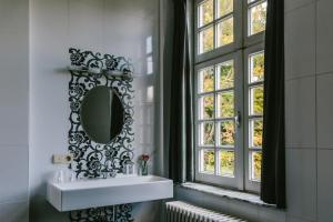 拉纳肯Kasteel Pietersheim的一间带水槽和镜子的浴室以及窗户。