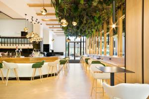 马德里巴拉哈斯美利亚酒店的一间设有绿色椅子的餐厅和一间酒吧
