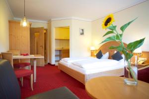 卑尔根萨尔茨堡霍夫酒店的酒店客房,设有一张床和一个带向日葵的花瓶