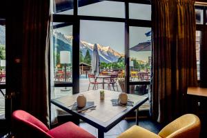 夏蒙尼-勃朗峰Excelsior Chamonix Hôtel & Spa的客房设有桌椅和大窗户。