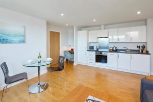 法恩伯勒HQ Aparthotel Farnborough的厨房以及带桌椅的起居室。
