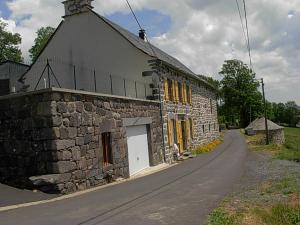 拉维西尔Vacances au pied des Monts du Cantal的路边的石头建筑,有黄色百叶窗