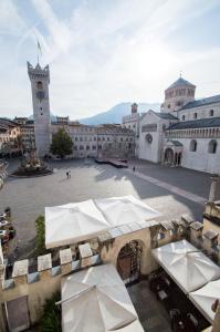 特伦托Scrigno del Duomo的一座带桌子和遮阳伞的庭院