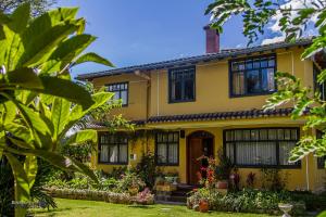 塔巴贝拉塔巴贝拉圣玛丽民宿的黄色的房子,有黑色的窗户和植物
